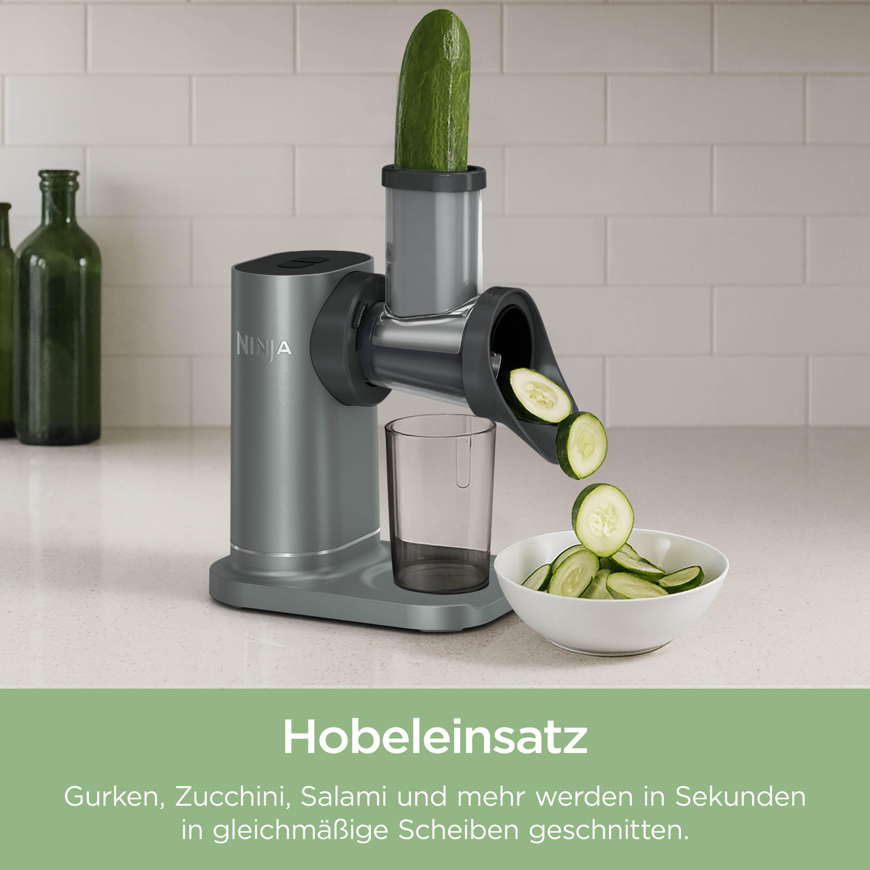 Ein Küchengerät schneidet Gurken in Scheiben. Eine Schüssel mit Scheiben steht daneben.