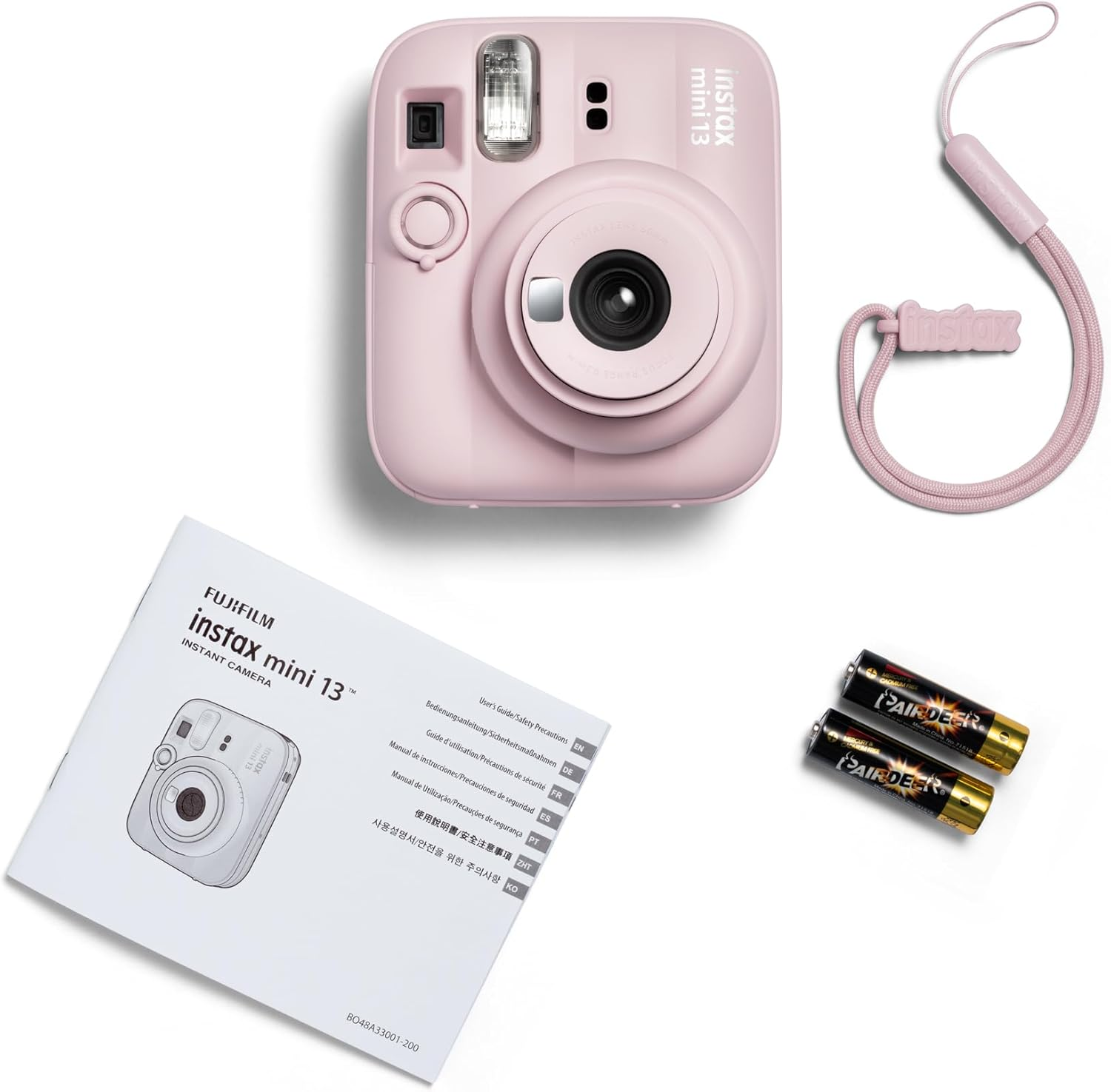 Egy rózsaszín Instax Mini 13 kamera csuklópánttal, kézikönyvvel és elemekkel.