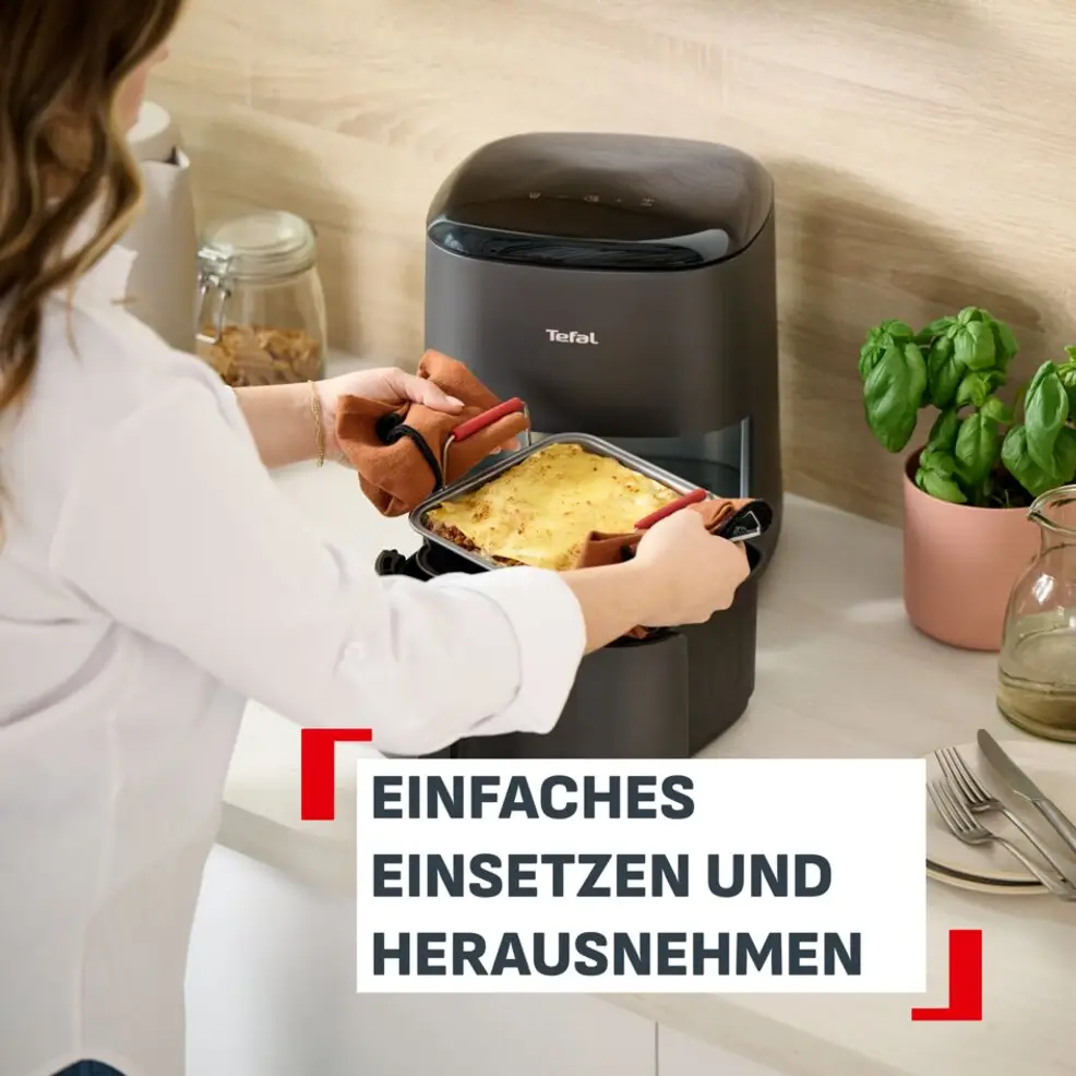 Une personne insère une lasagne dans une friteuse à air Tefal.