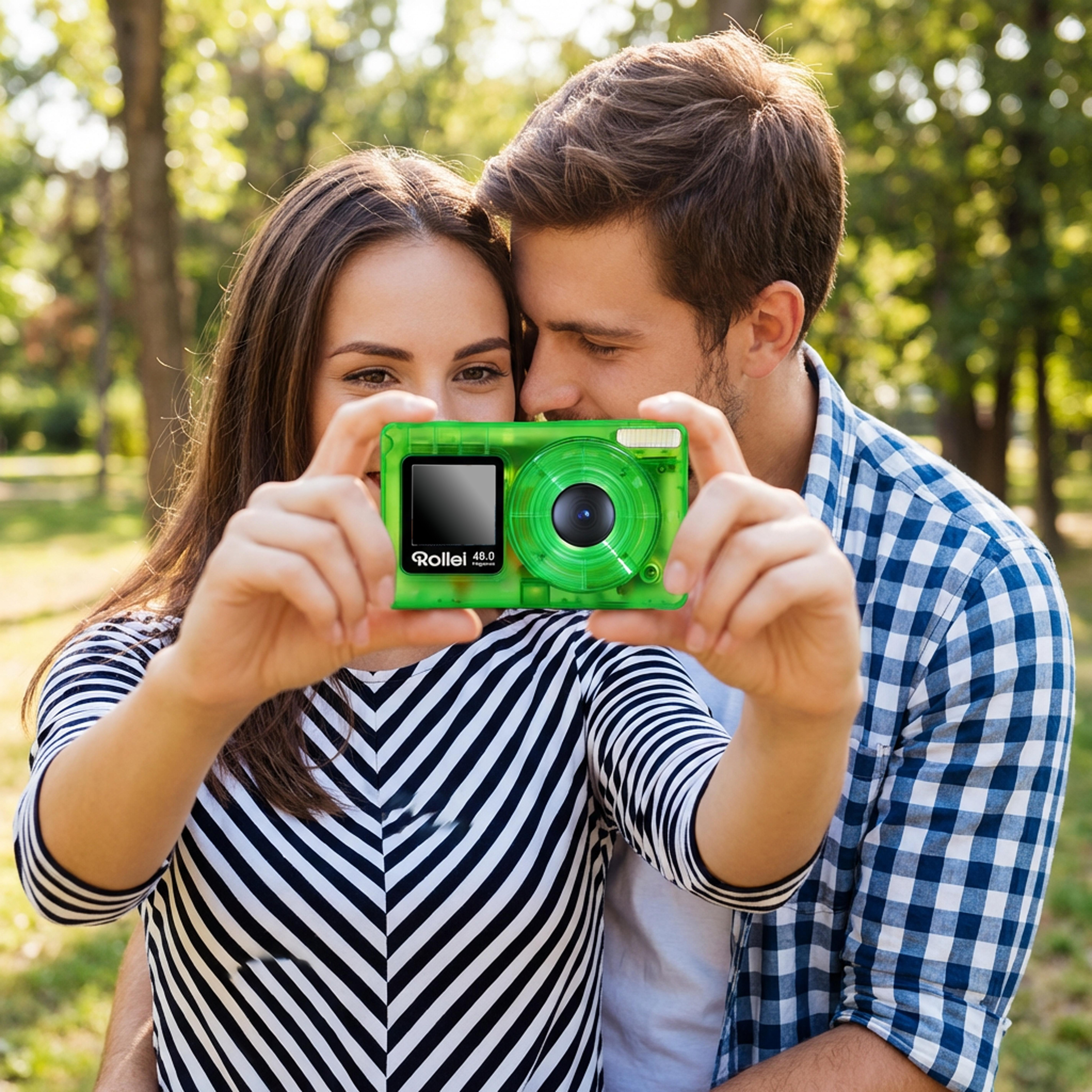 Ein Paar macht ein Selfie mit einer grünen Kamera in einem Park.