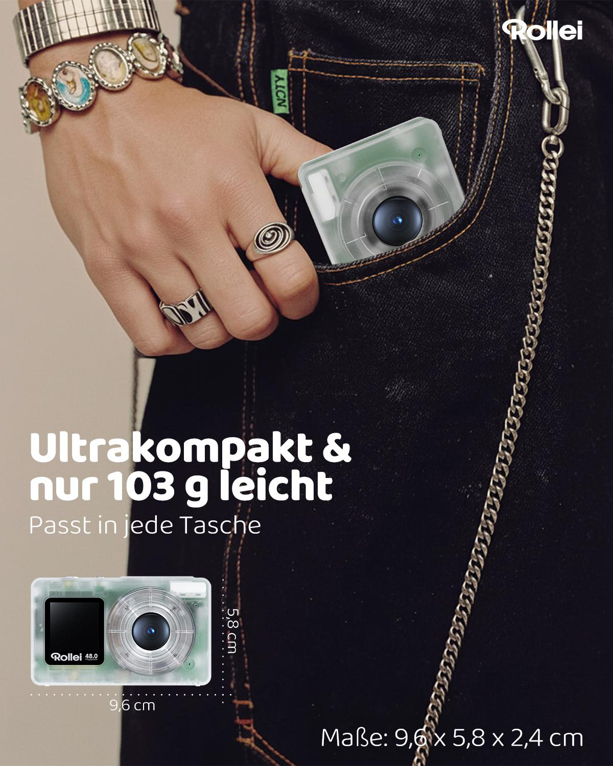 Eine Hand mit Schmuck steckt eine kleine weiße Kamera in eine Jeanstasche.