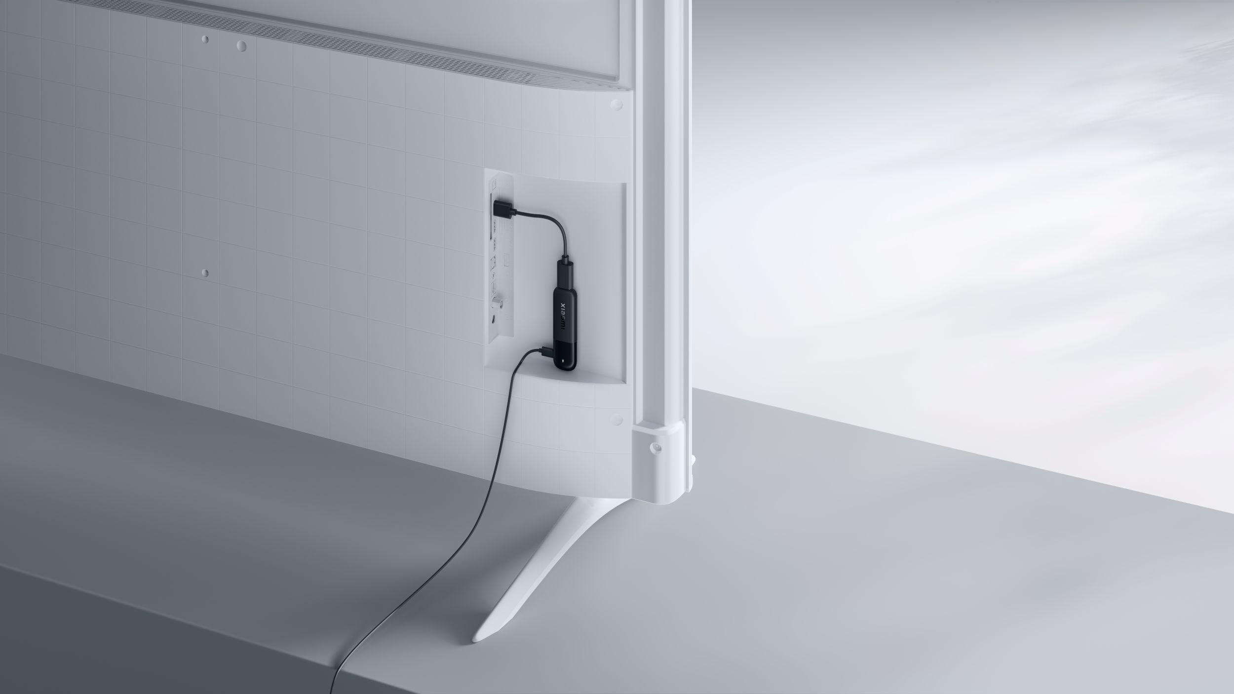 Ein schwarzer Dongle ist in den seitlichen Anschluss eines weißen Fernsehers eingesteckt.