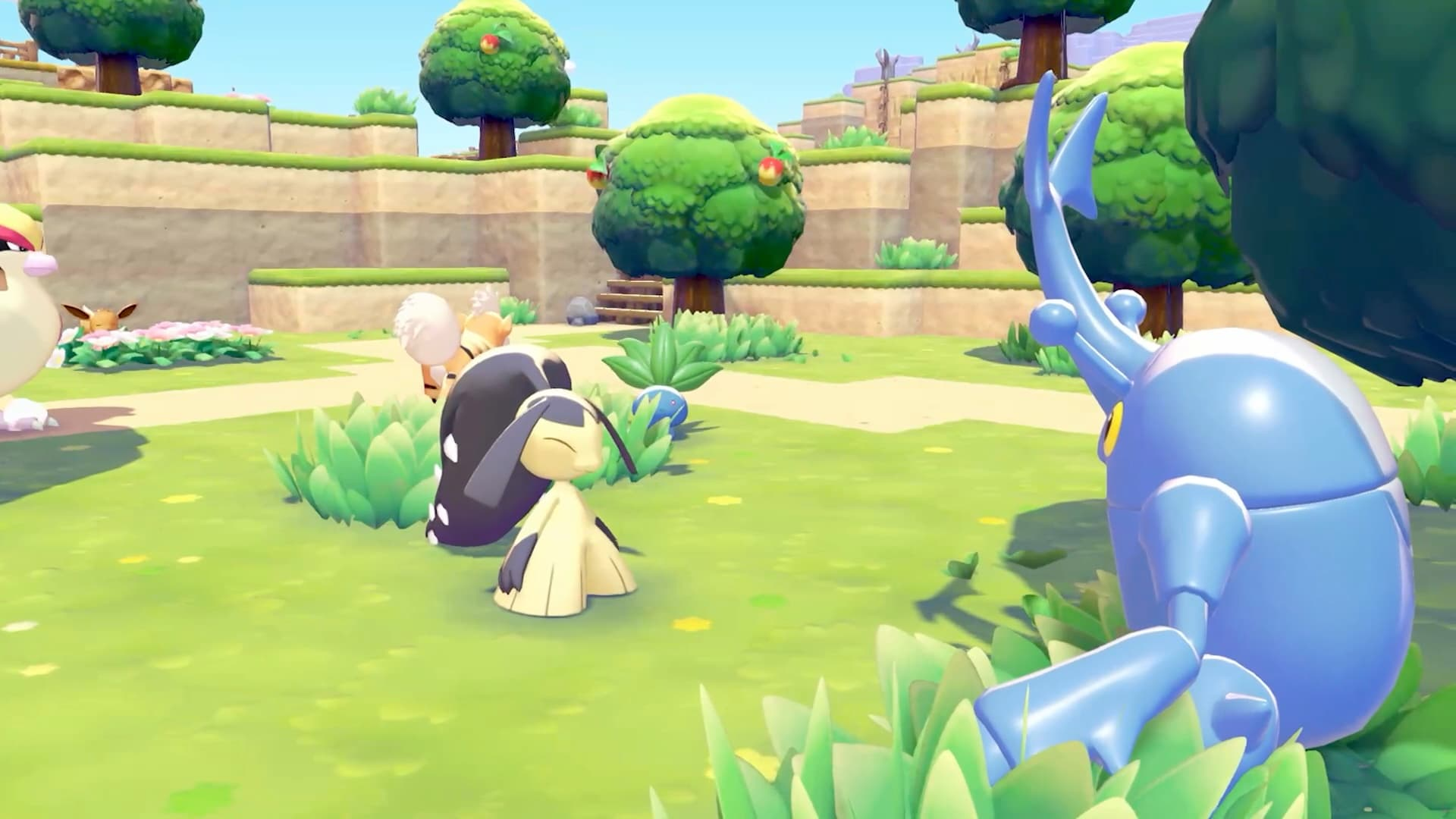 Un Pokémon scarabée bleu est assis dans l'herbe près d'un Pokémon jaune. Arbres et collines en arrière-plan.