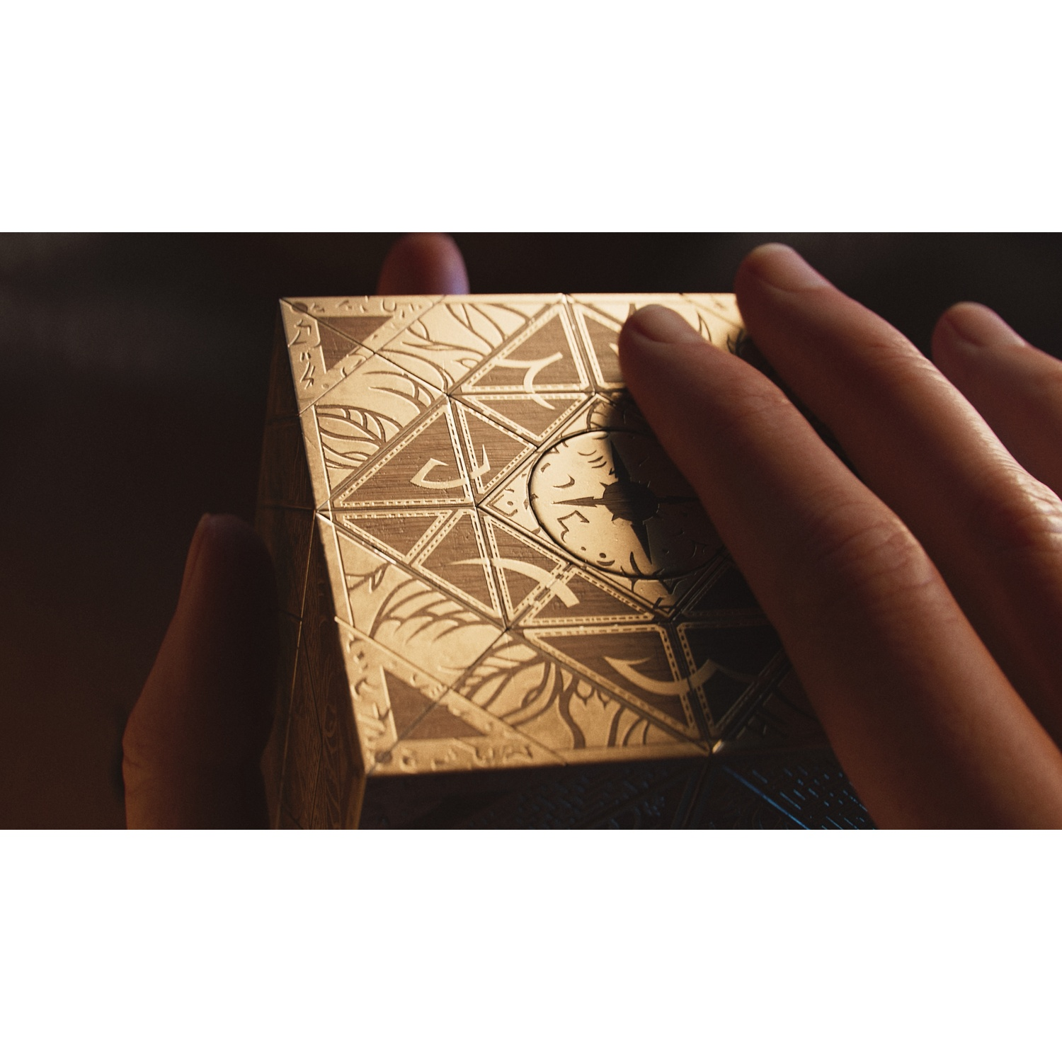 Handen houden een gouden puzzeldoos met ingewikkelde geometrische patronen en symbolen vast.