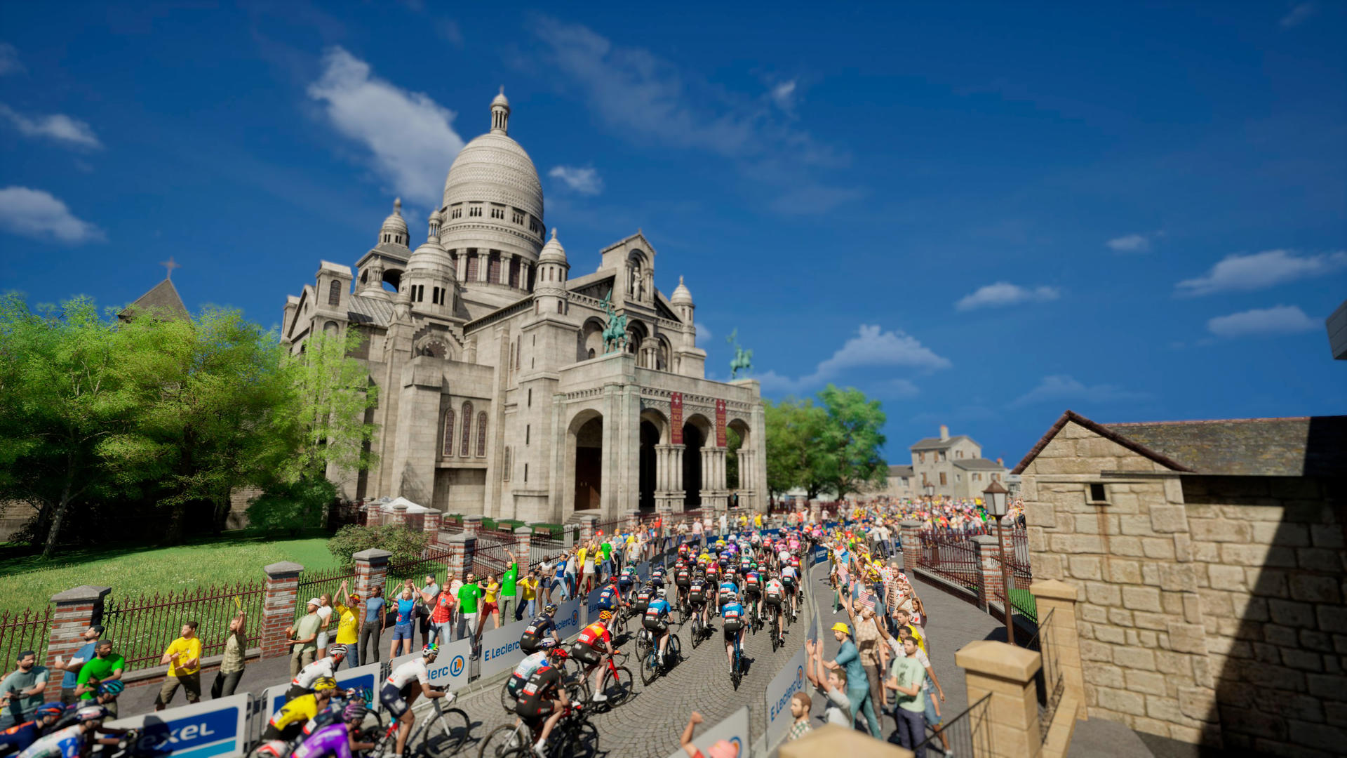 Radsportler fahren an der Basilika Sacré-Cœur vorbei, Zuschauer winken.