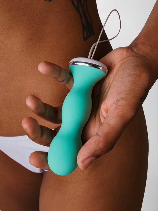 Eine Hand hält einen türkisfarbenen Vibrator mit silbernen Akzenten.