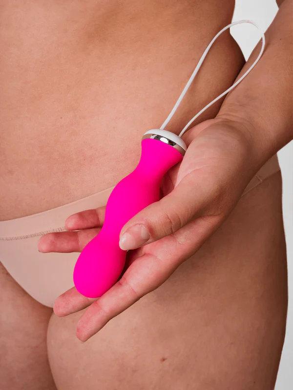 Eine Hand hält einen leuchtend pinken Vibrator mit einem weißen Kordelzug.