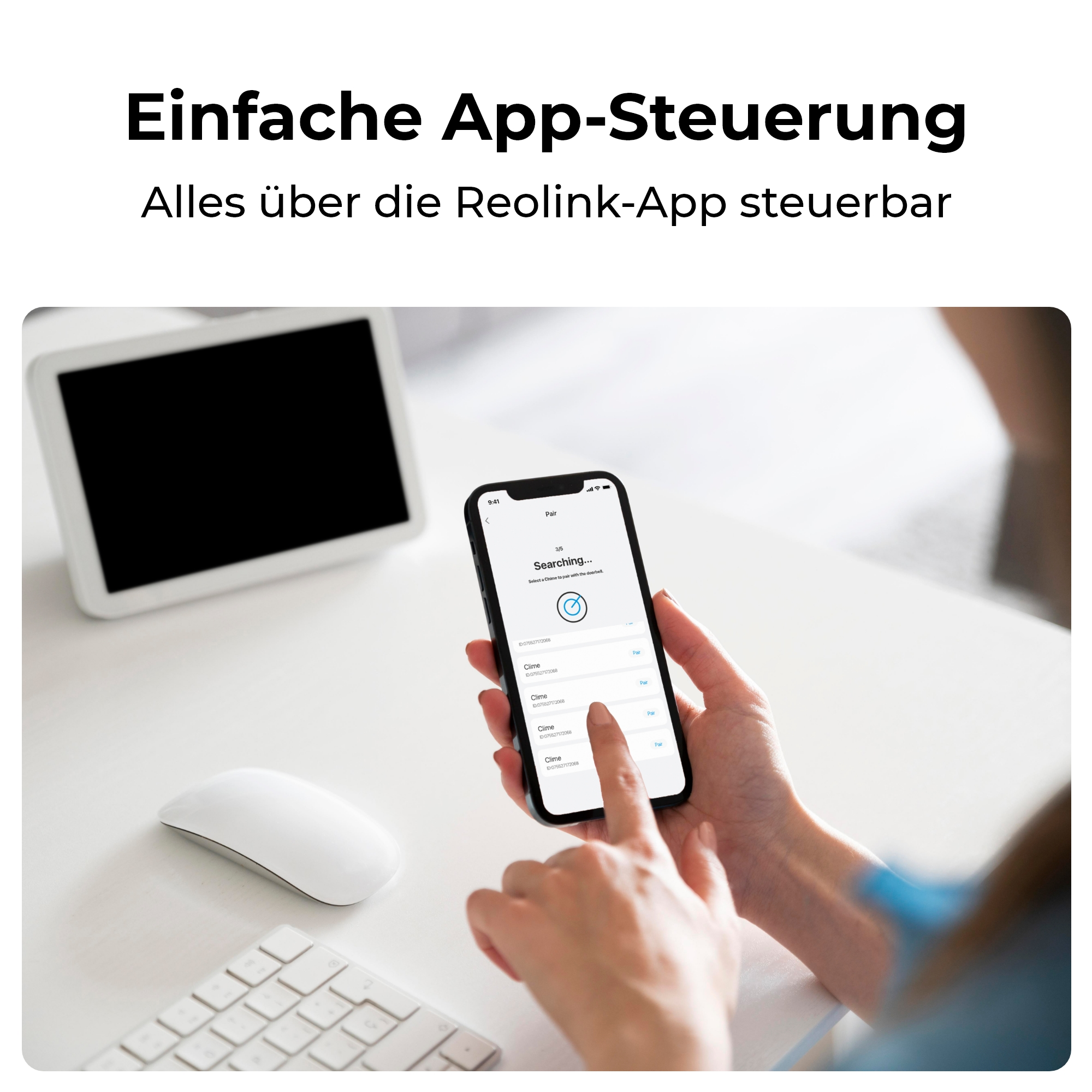 Eine Hand hält ein Smartphone mit einer Suchanzeige. Ein weißer Monitor und eine Maus sind daneben.