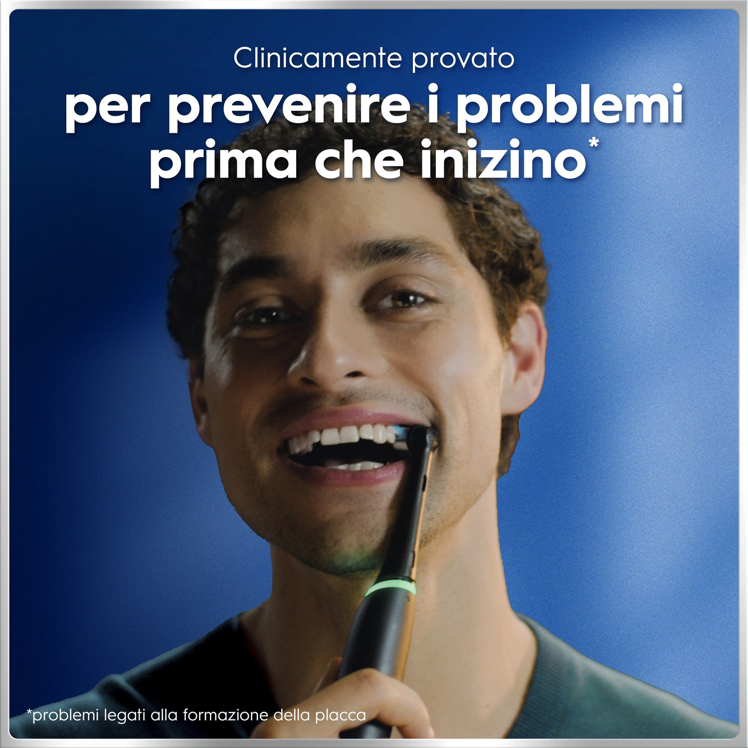 Uomo si lava i denti con spazzolino elettrico su sfondo blu.