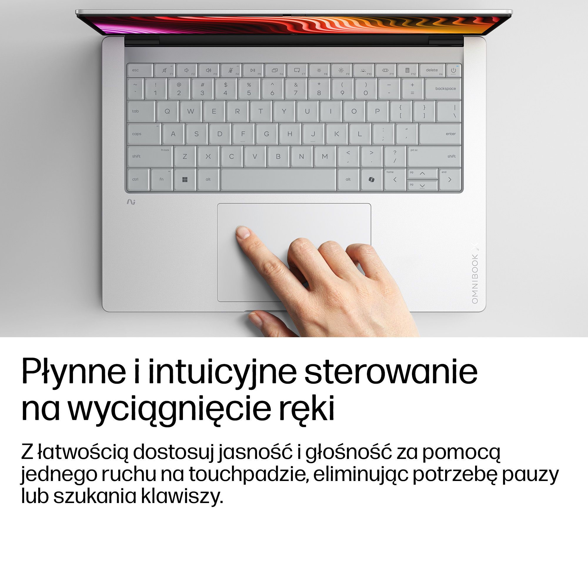Dłoń obsługuje touchpad jasnoszarego laptopa z podświetlaną klawiaturą.