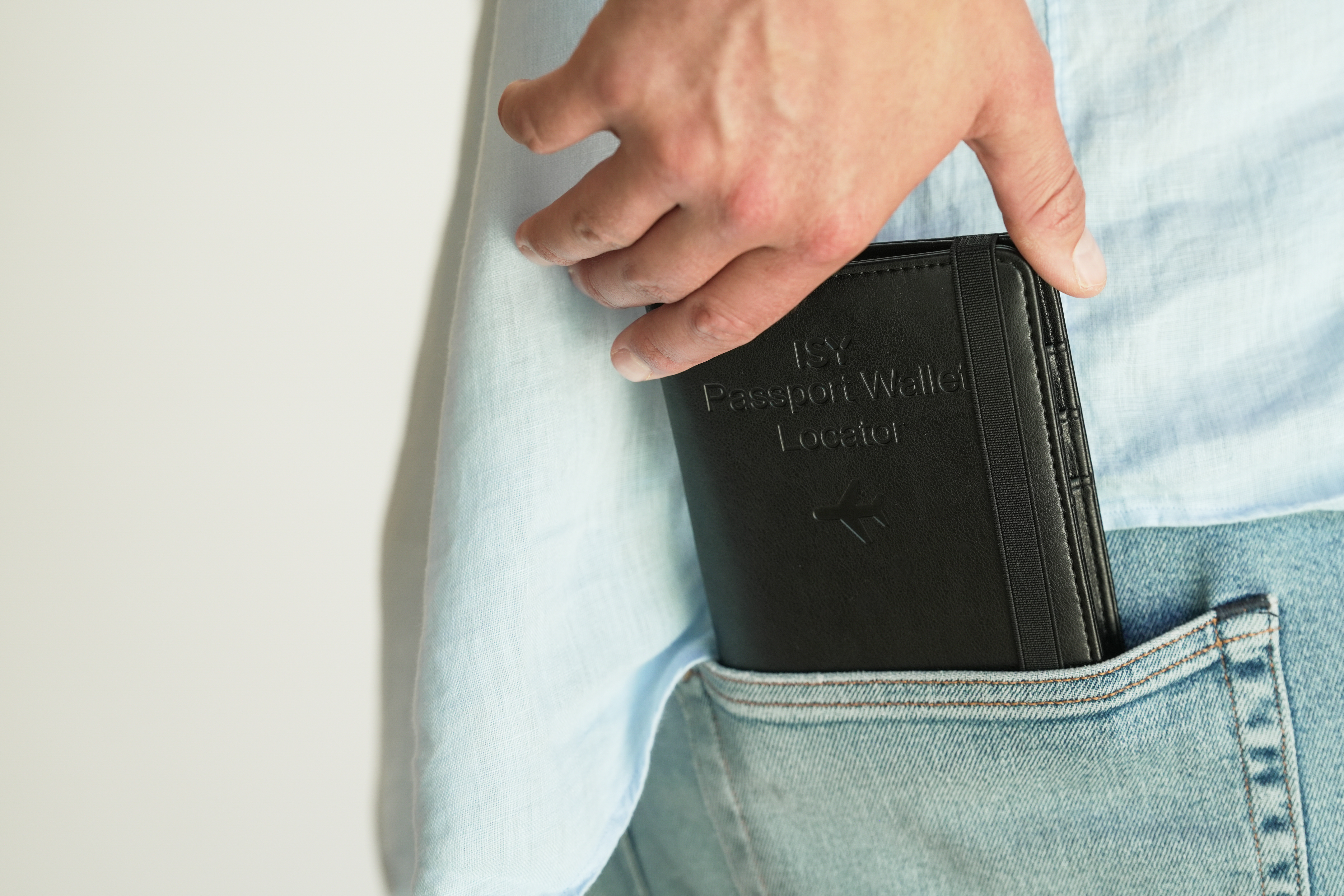 Mann steckt schwarzes Pass-Etui mit Flugzeuglogo in die Hosentasche.