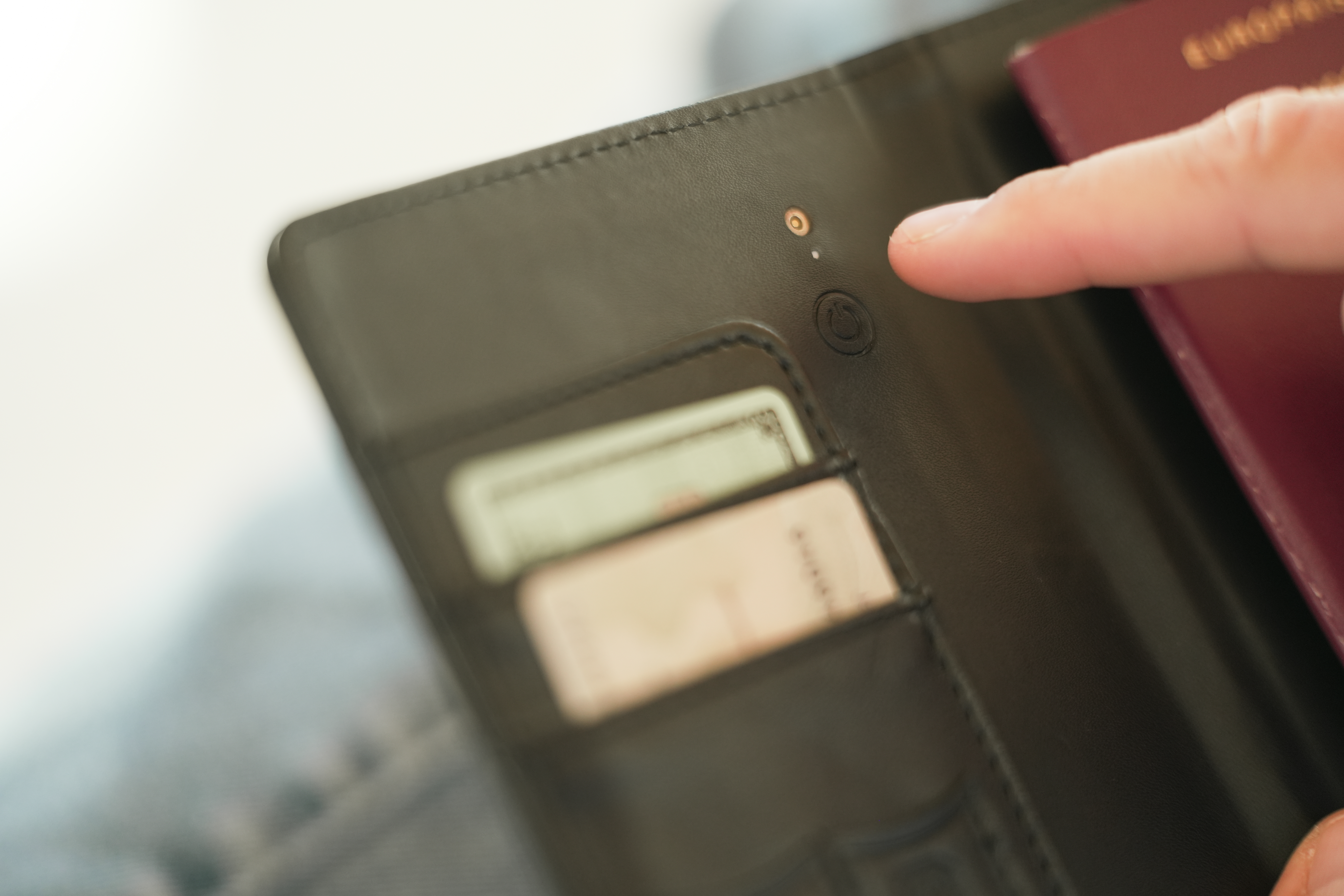 Eine Hand berührt eine schwarze Brieftasche mit Karten und einem roten Reisepass.
