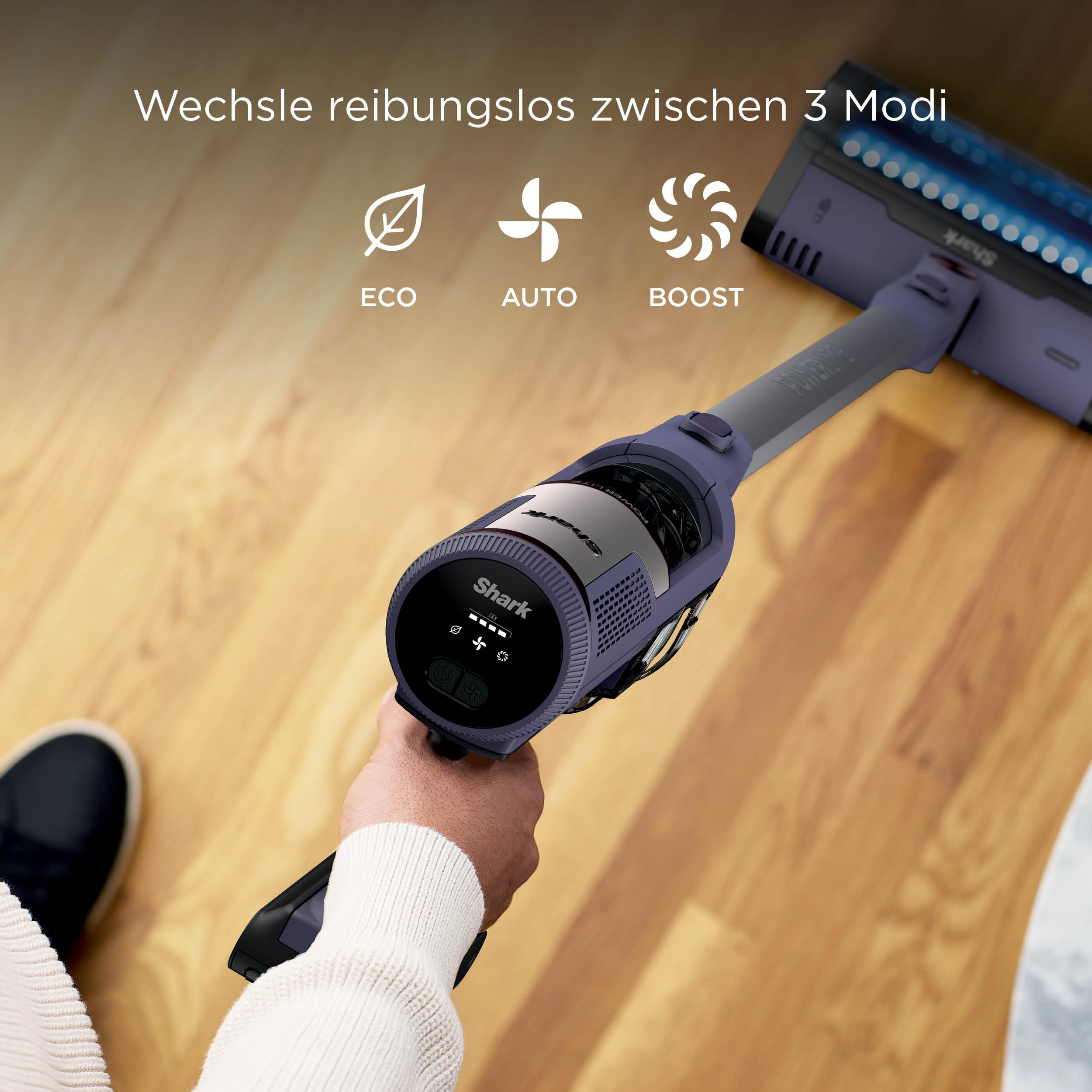 Hand hält Staubsauger mit 3 Modi: Eco, Auto, Boost. Holzfußboden im Hintergrund.