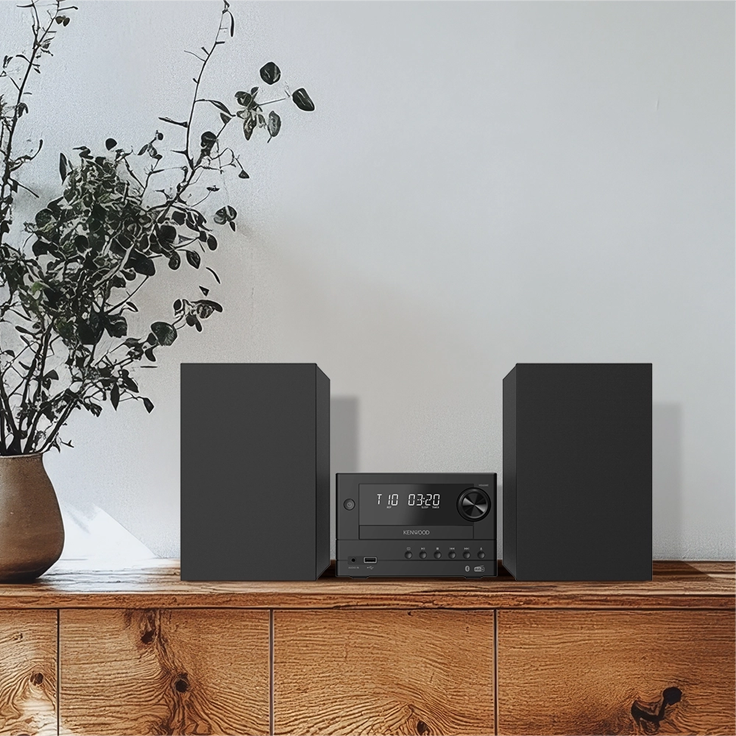 Een zwart Kenwood stereosysteem met twee luidsprekers op een houten plank.