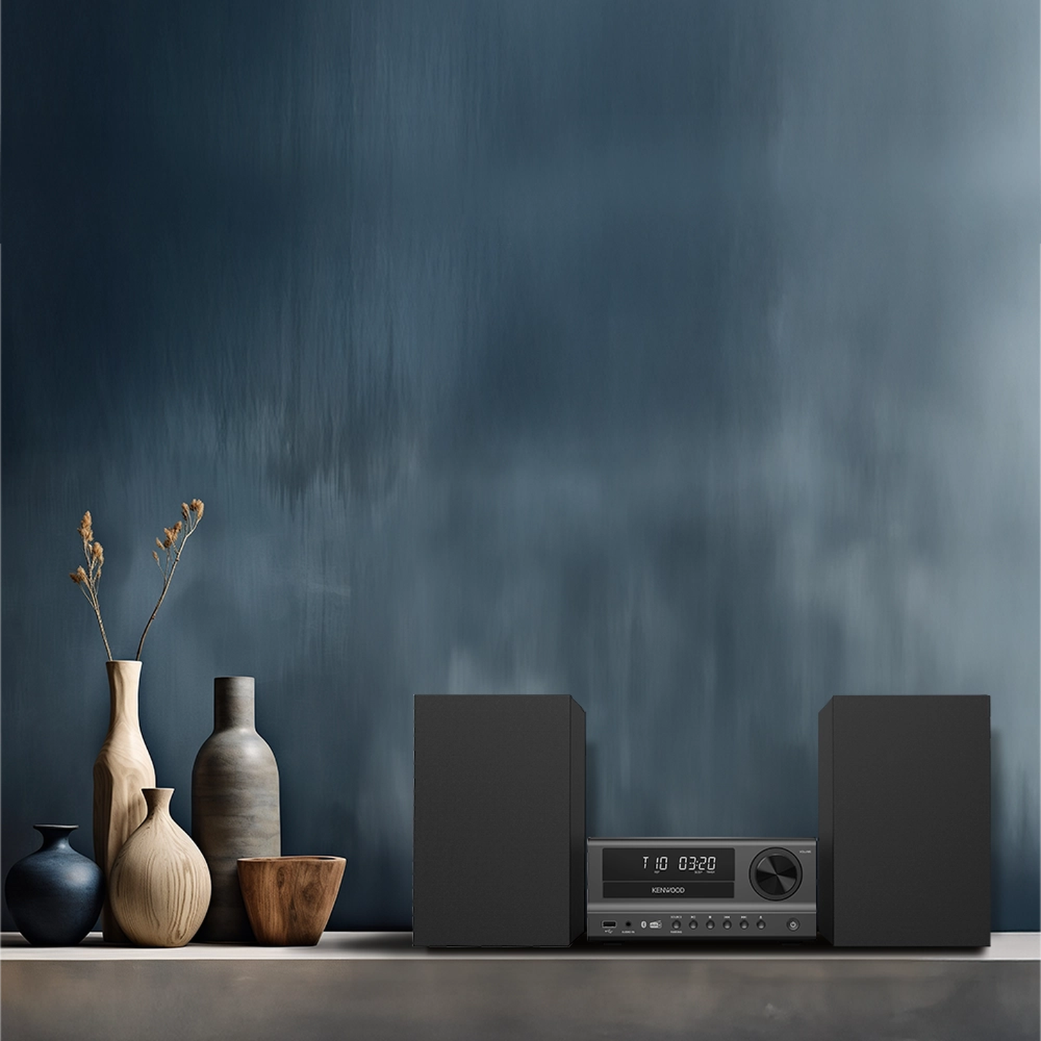 Een Kenwood stereosysteem met twee luidsprekers en een hoofdunit op een plank.