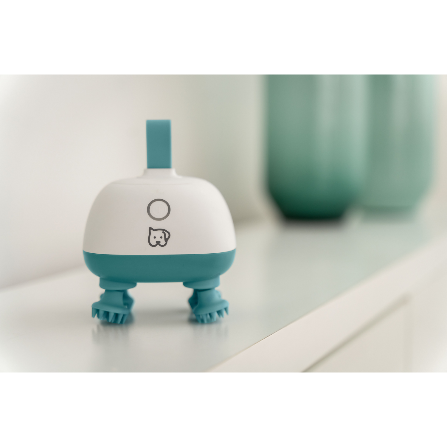 Een witte en turquoise huisdierverzorgingsborstelkop met vier kleine borstelvoetjes.