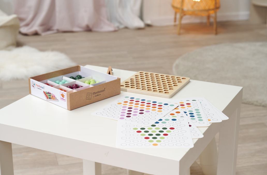 Ein Montessori-Sortierspiel mit bunten Perlen, Legeplättchen und einem Holzbrett.