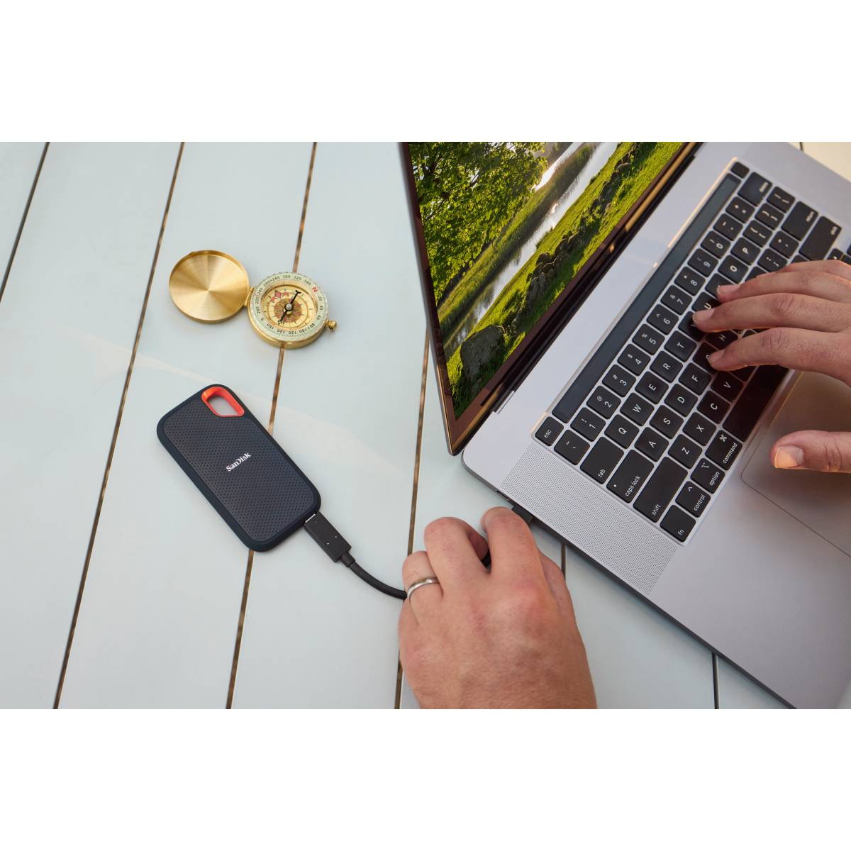 Un portátil con disco externo y brújula sobre una mesa de madera.