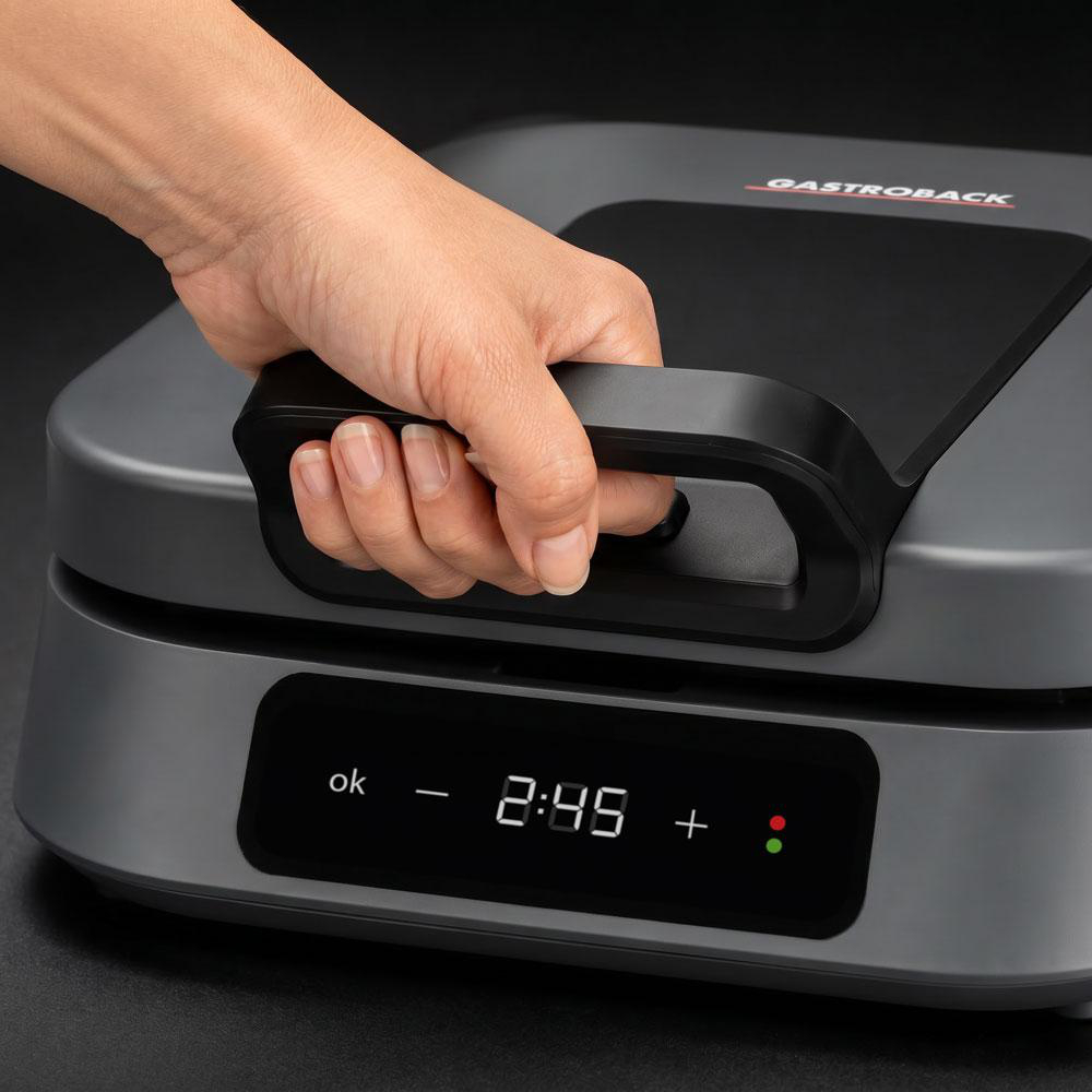 Eine Hand greift nach dem Griff eines dunklen Geräts mit digitaler Anzeige.