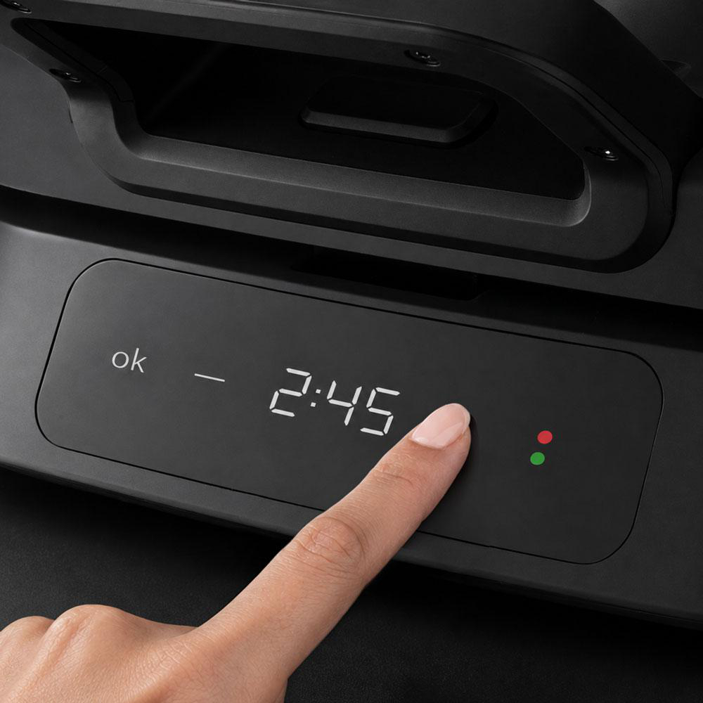 Eine Hand berührt einen Bildschirm mit der Aufschrift „ok – 2:45“ und zwei Lichtern.