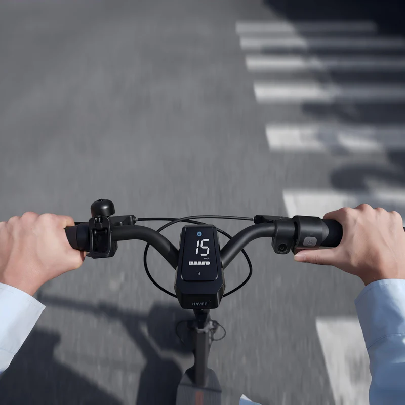Hände steuern E-Scooter mit Display auf einem Zebrastreifen.