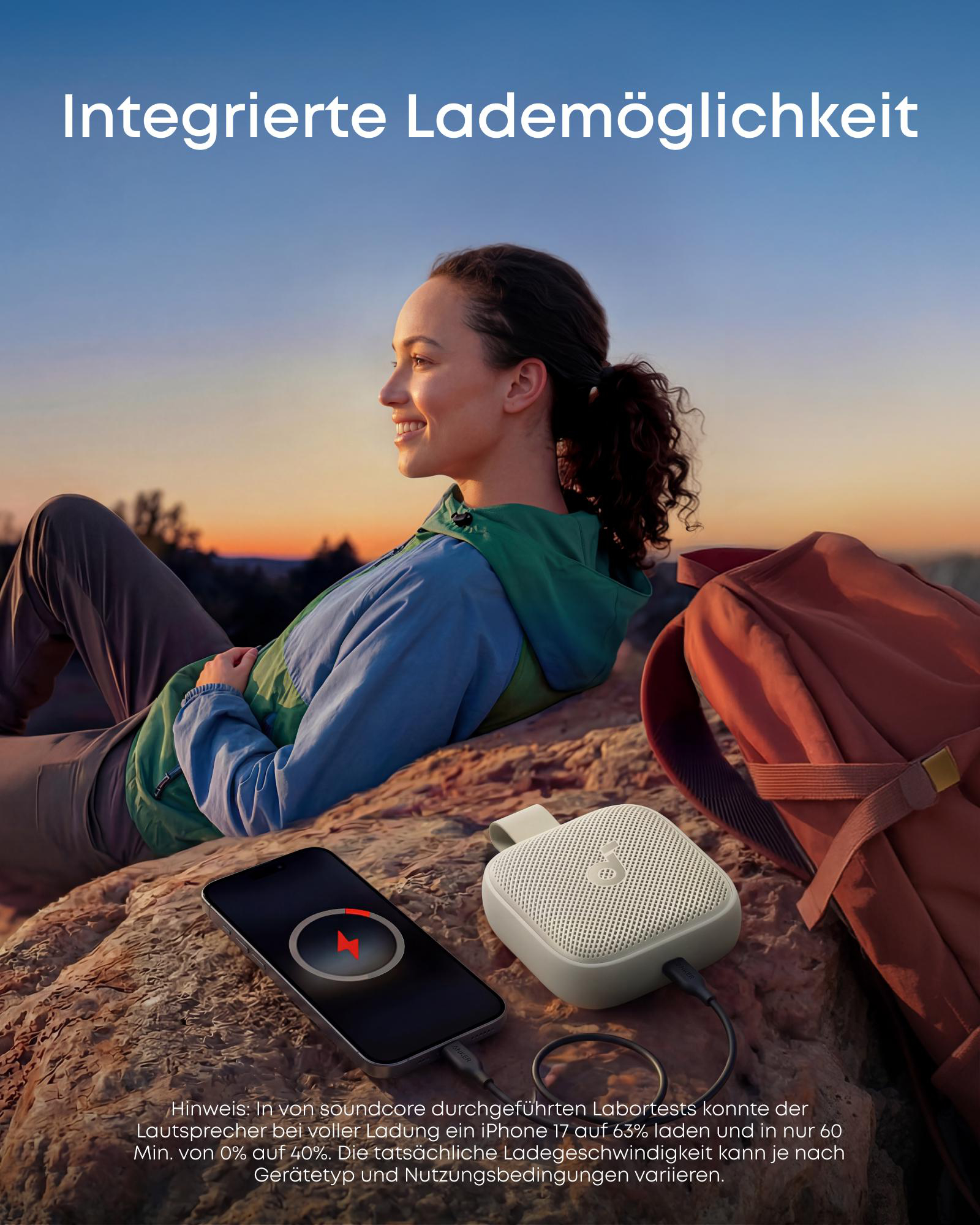 Eine Frau sitzt im Freien, ein Smartphone und ein Lautsprecher sind sichtbar.