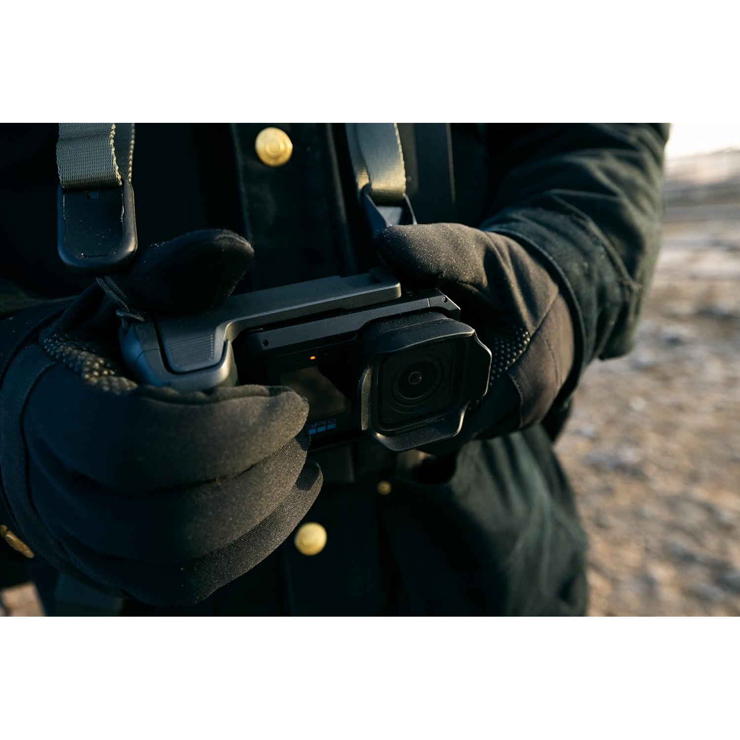 Person in black gloves holding an action camera.