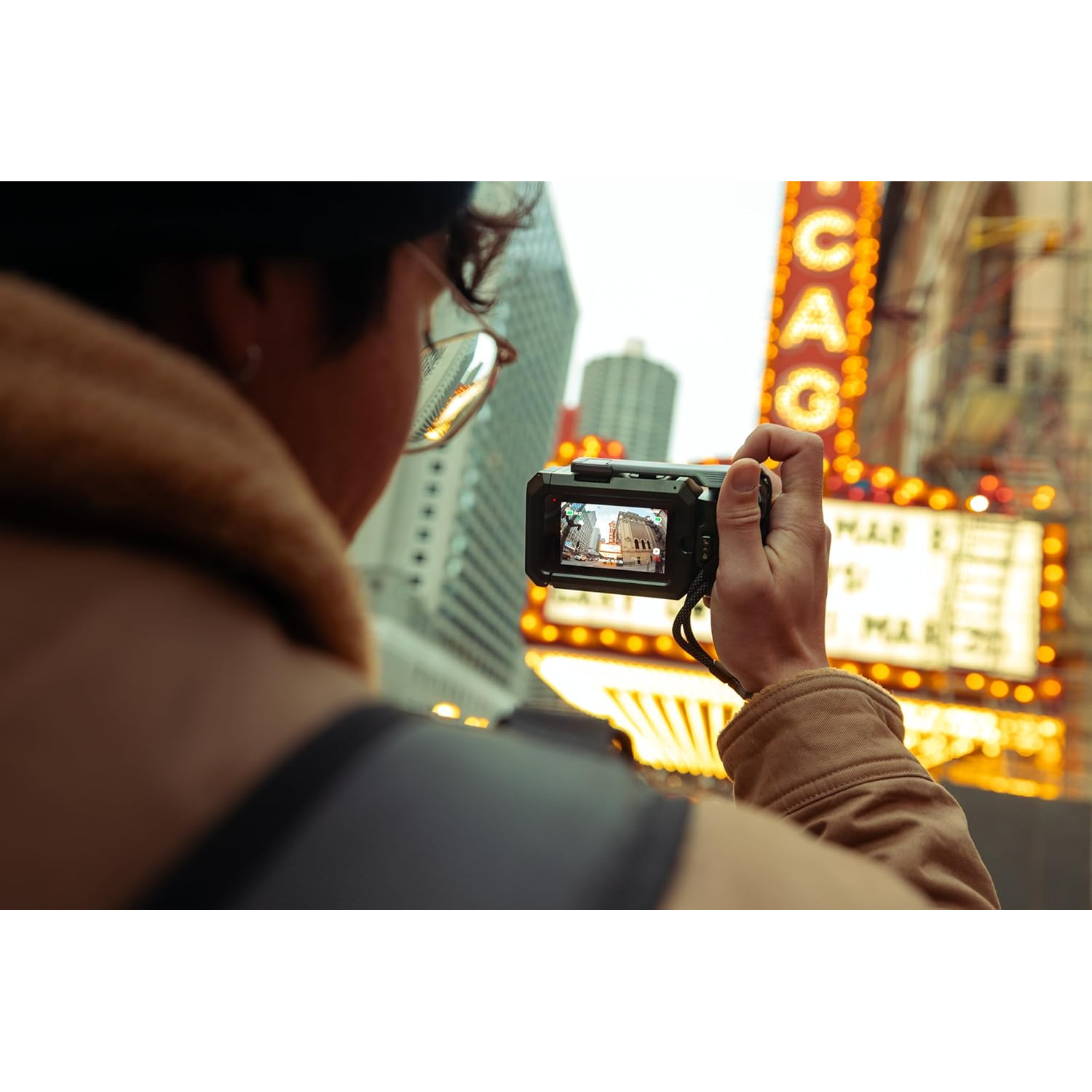 A person photographs a lit theater with a camera.