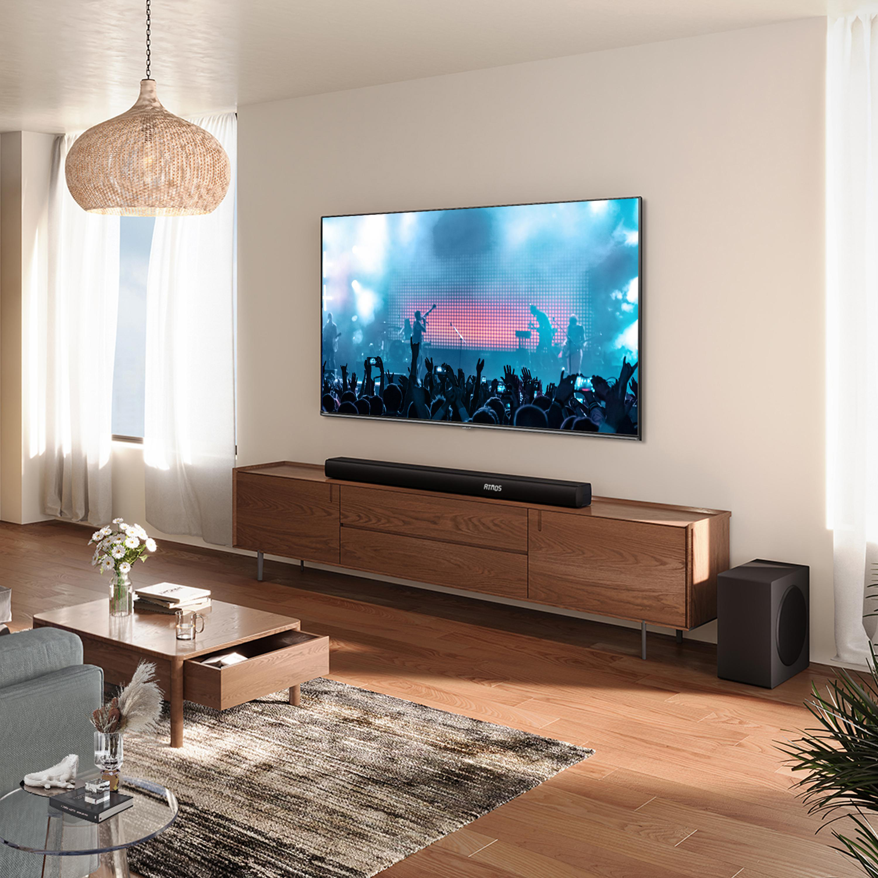 Ein Wohnzimmer mit Fernseher, der ein Konzert zeigt, und Holzmöbeln.