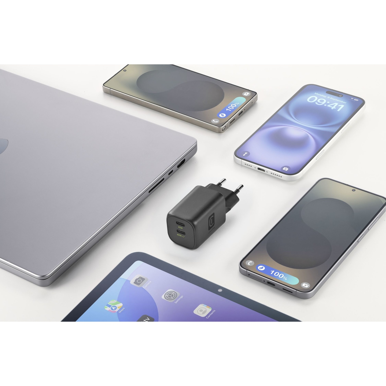 Un laptop, un caricabatterie e tre smartphone disposti su una superficie bianca.