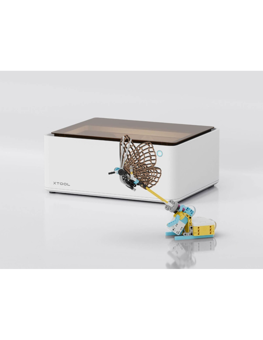 Una mariposa de madera sobre un dispositivo XTOOL blanco con construcción Lego.
