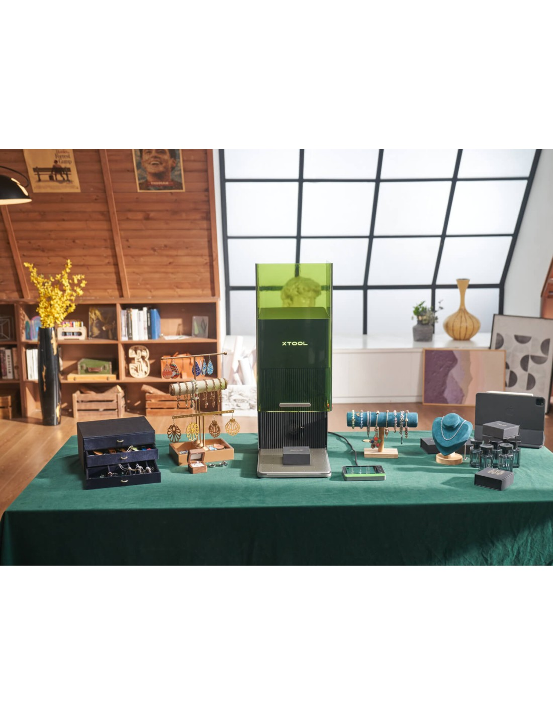 Un dispositivo XTOOL verde está sobre una mesa mostrando joyas y cajas.