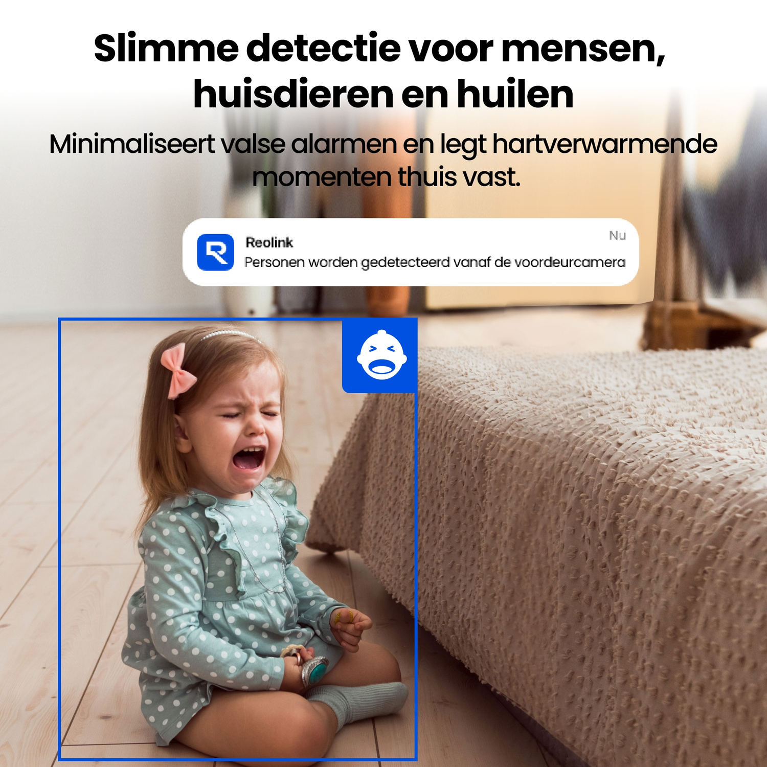 Een huilende peuter zit op een houten vloer naast een bed.