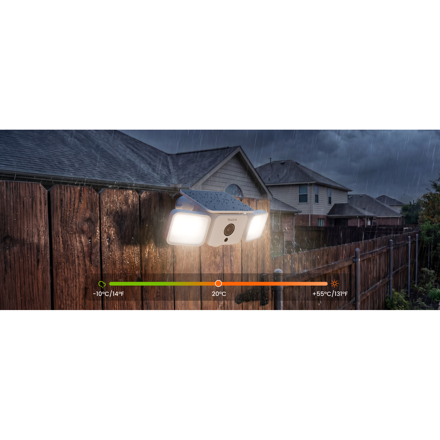 A white motion detector with camera mounted on a wooden fence in the rain.