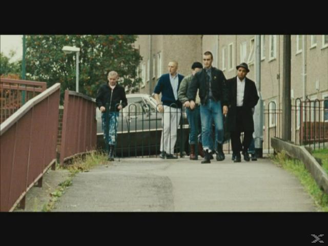 Eine Gruppe Männer in Lederjacken und Jeans geht auf einem Weg.