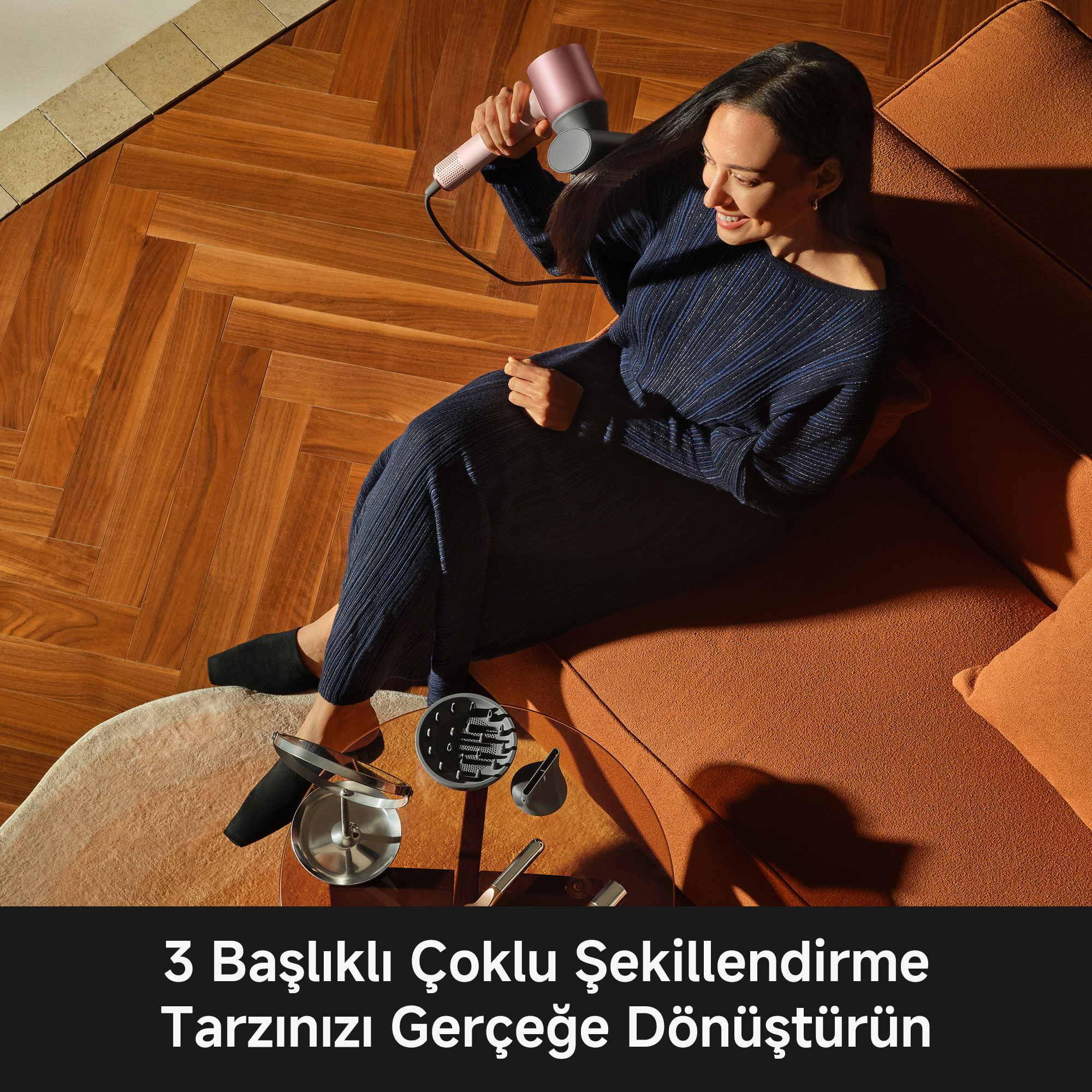 Kadın, koltukta otururken pembe saç kurutma makinesiyle saçını kurutuyor.
