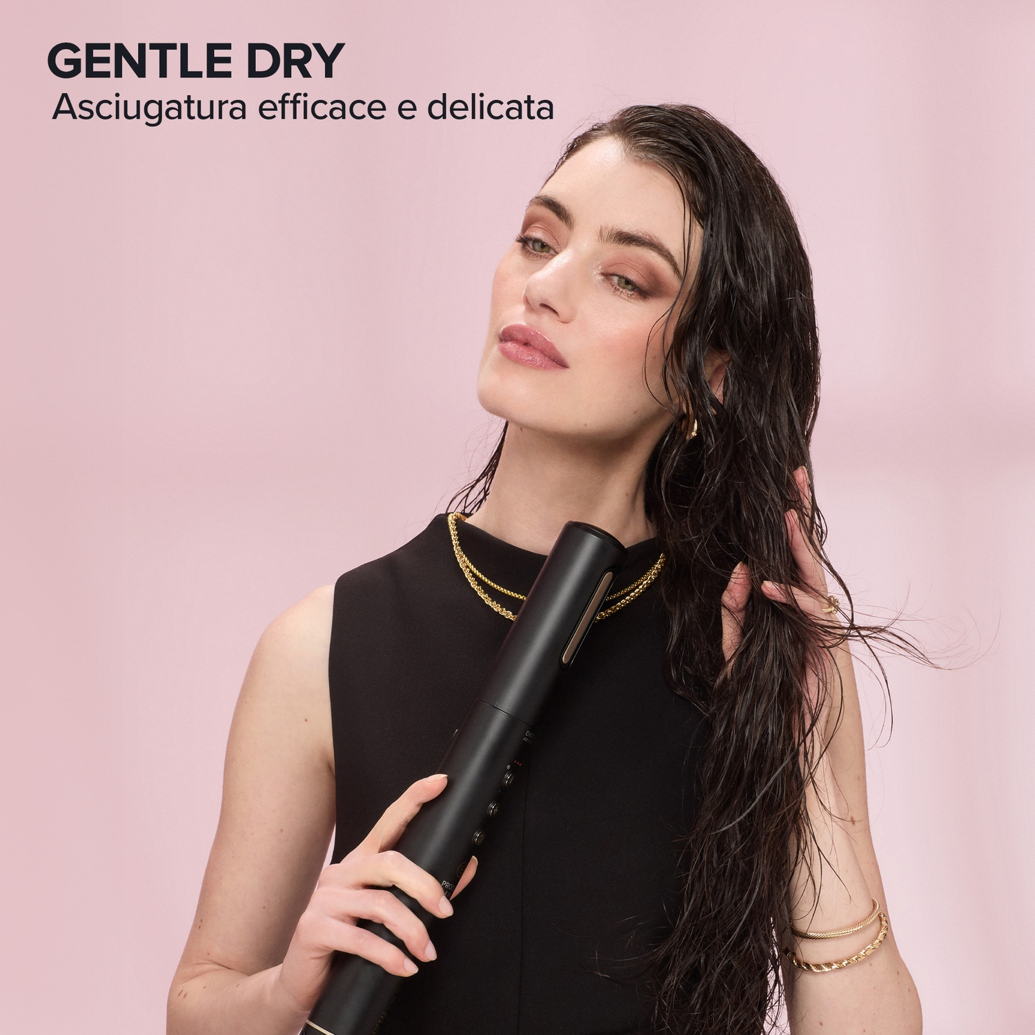 Una donna con i capelli bagnati tiene in mano un asciugacapelli nero, acconciandosi i capelli.