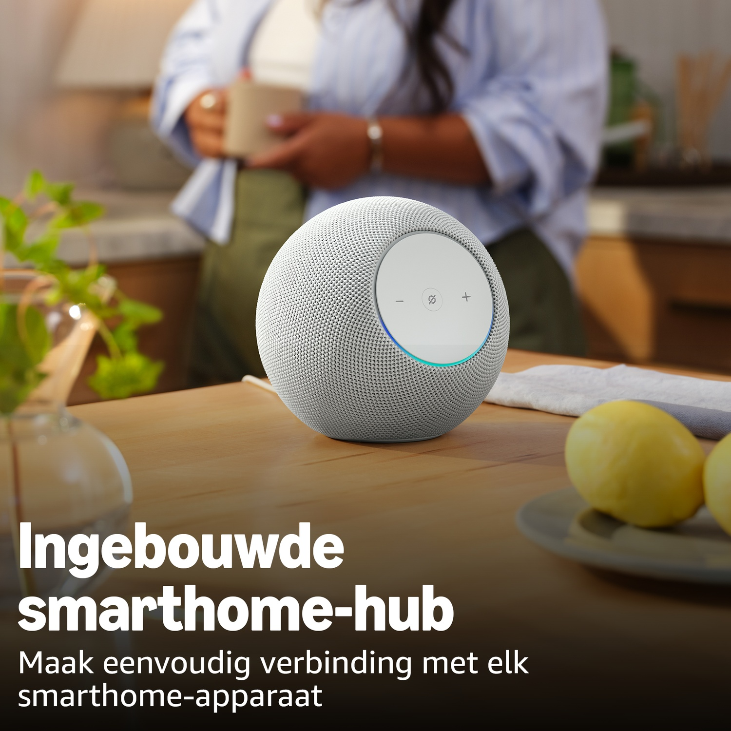 Gray smart speaker on a wooden table with lemons and a woman in the background.