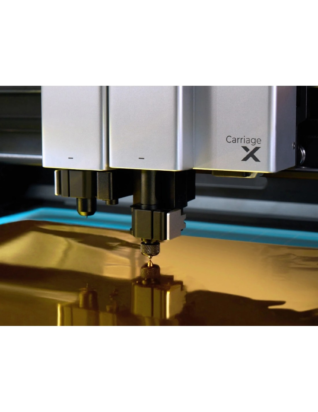 Un cabezal de plotter con aguja toca una superficie de lámina dorada.
