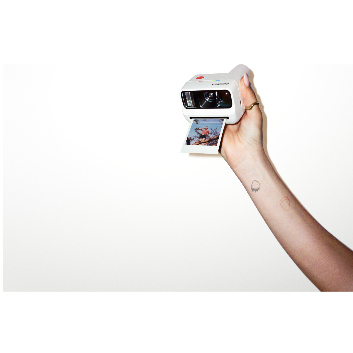 Een hand houdt een witte instant camera vast met een uitkomende foto.