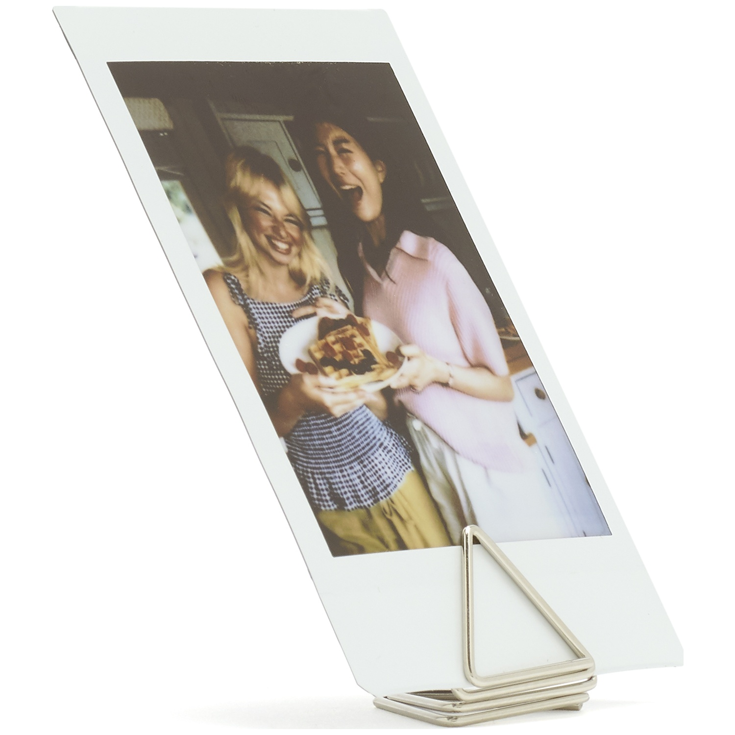 Two women laugh while holding a plate of waffles.