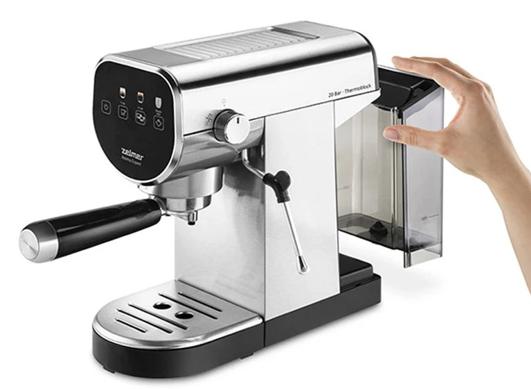 Ręka wyjmuje zbiornik na wodę ze srebrnej maszyny do espresso.
