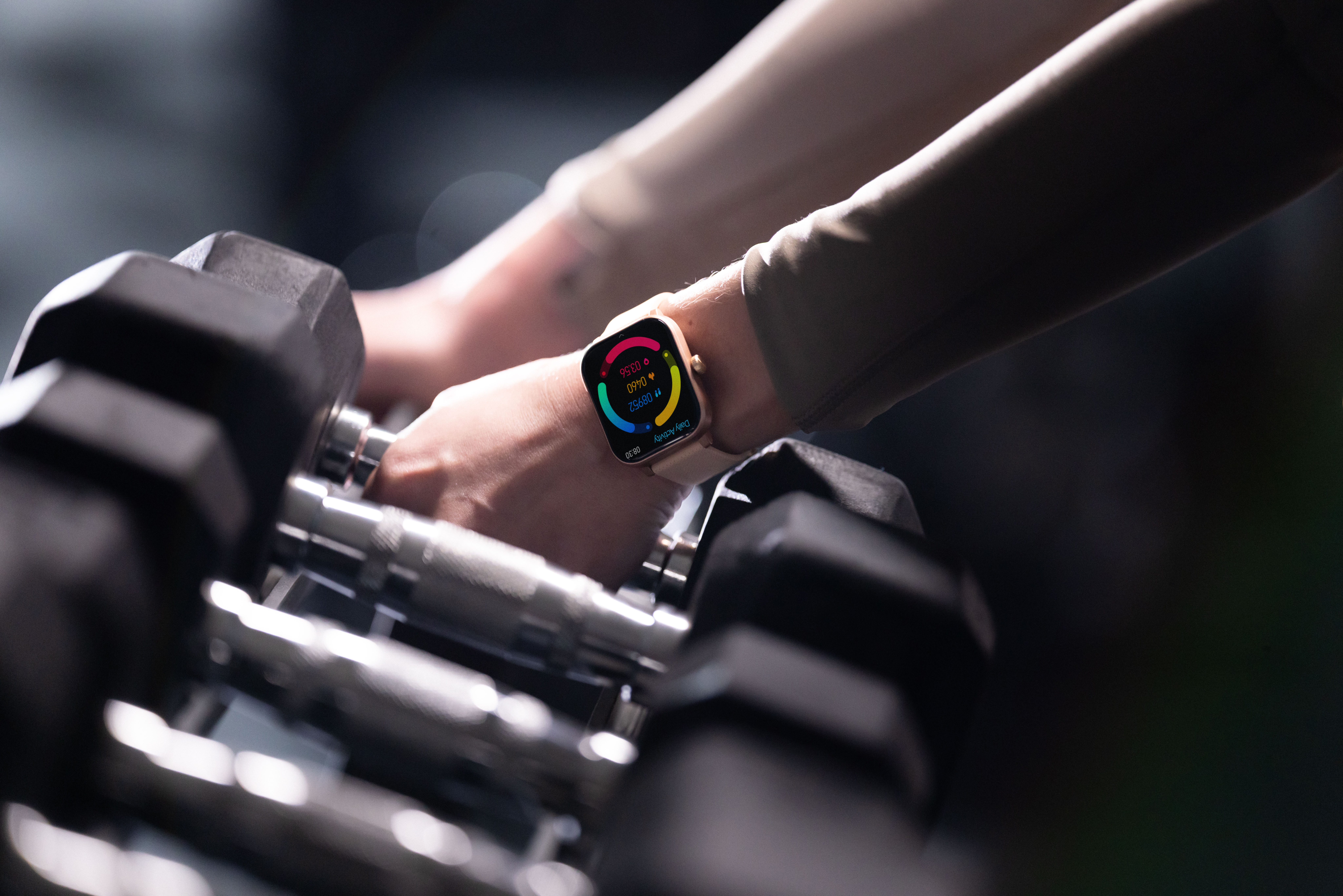 Eine Hand greift nach Hanteln, eine Smartwatch zeigt Aktivitätsdaten an.
