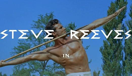 Steve Reeves wirft mit einem Speer vor blauem Himmel und Bäumen.