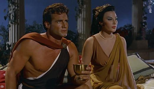 Ein Mann mit einem roten Umhang und eine Frau in einem goldenen Kleid sitzen nebeneinander.