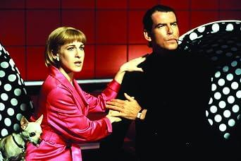 Eine Frau in einem rosa Blazer mit einem Chihuahuawelpen und ein Mann in Schwarz.