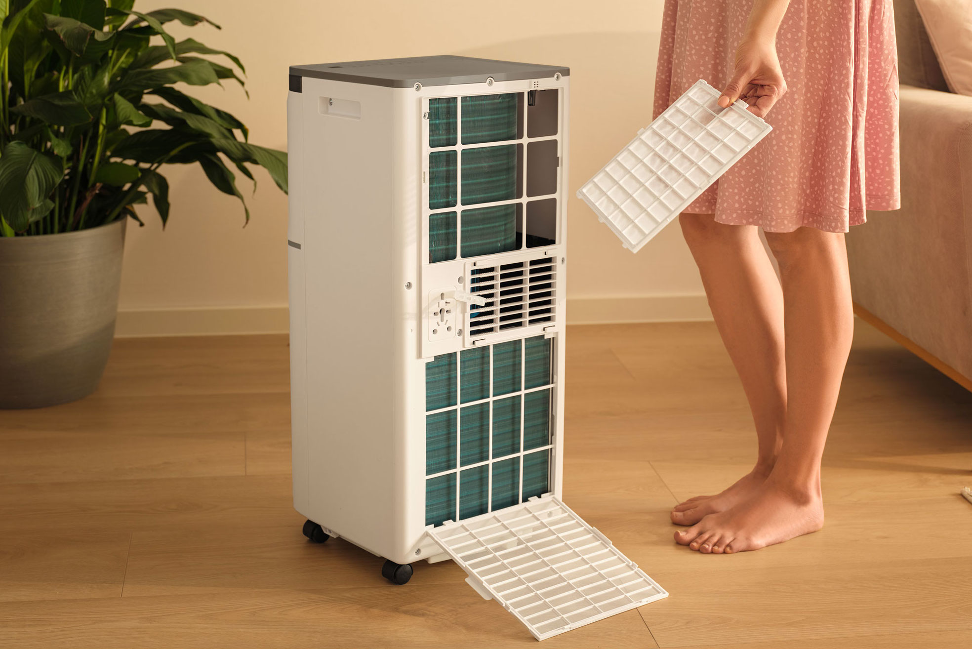 Osoba wymieniająca filtr białego przenośnego klimatyzatora.
