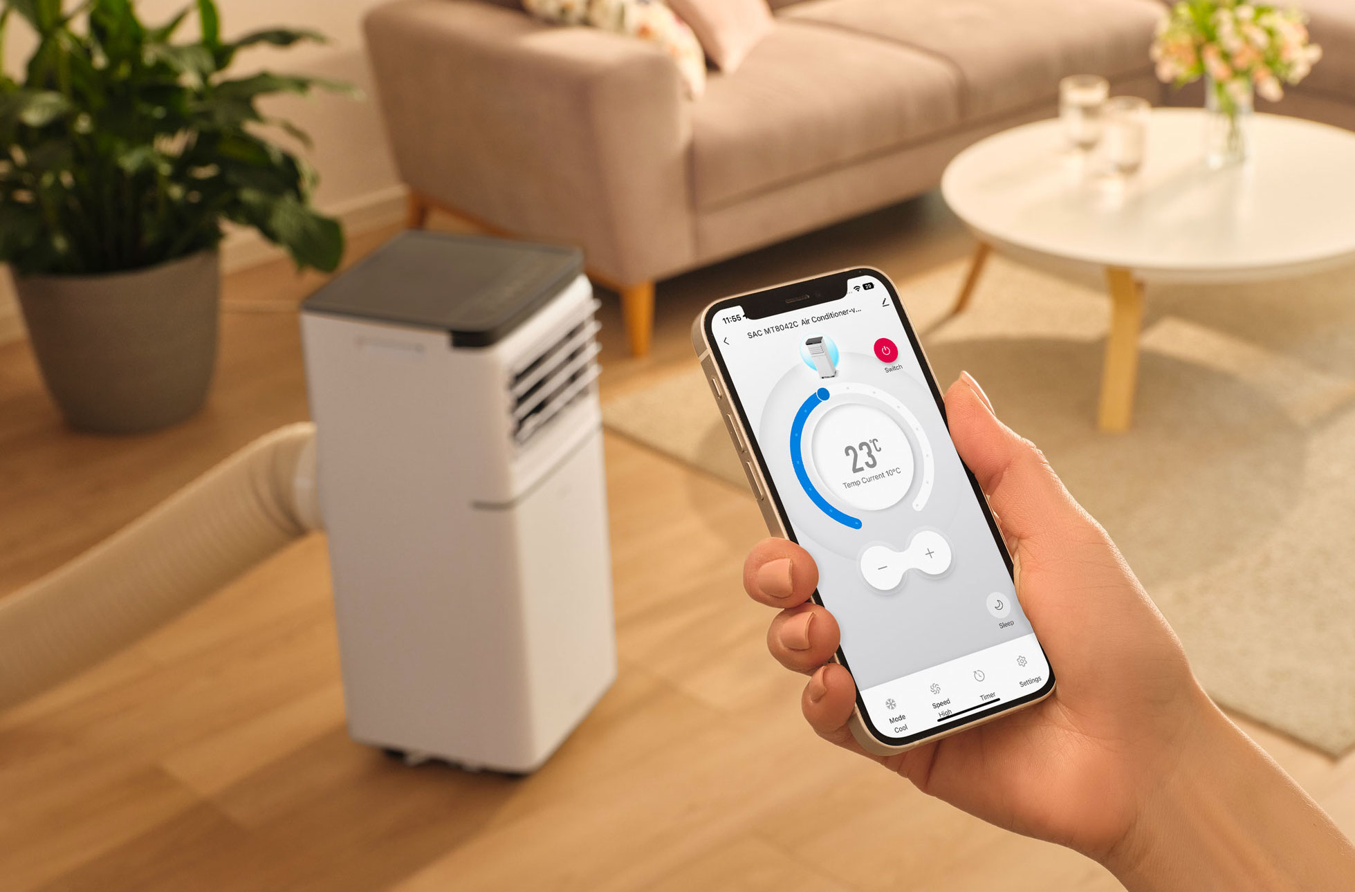 Biała przenośna klimatyzacja z wężem i smartfonem pokazującym aplikację sterującą.