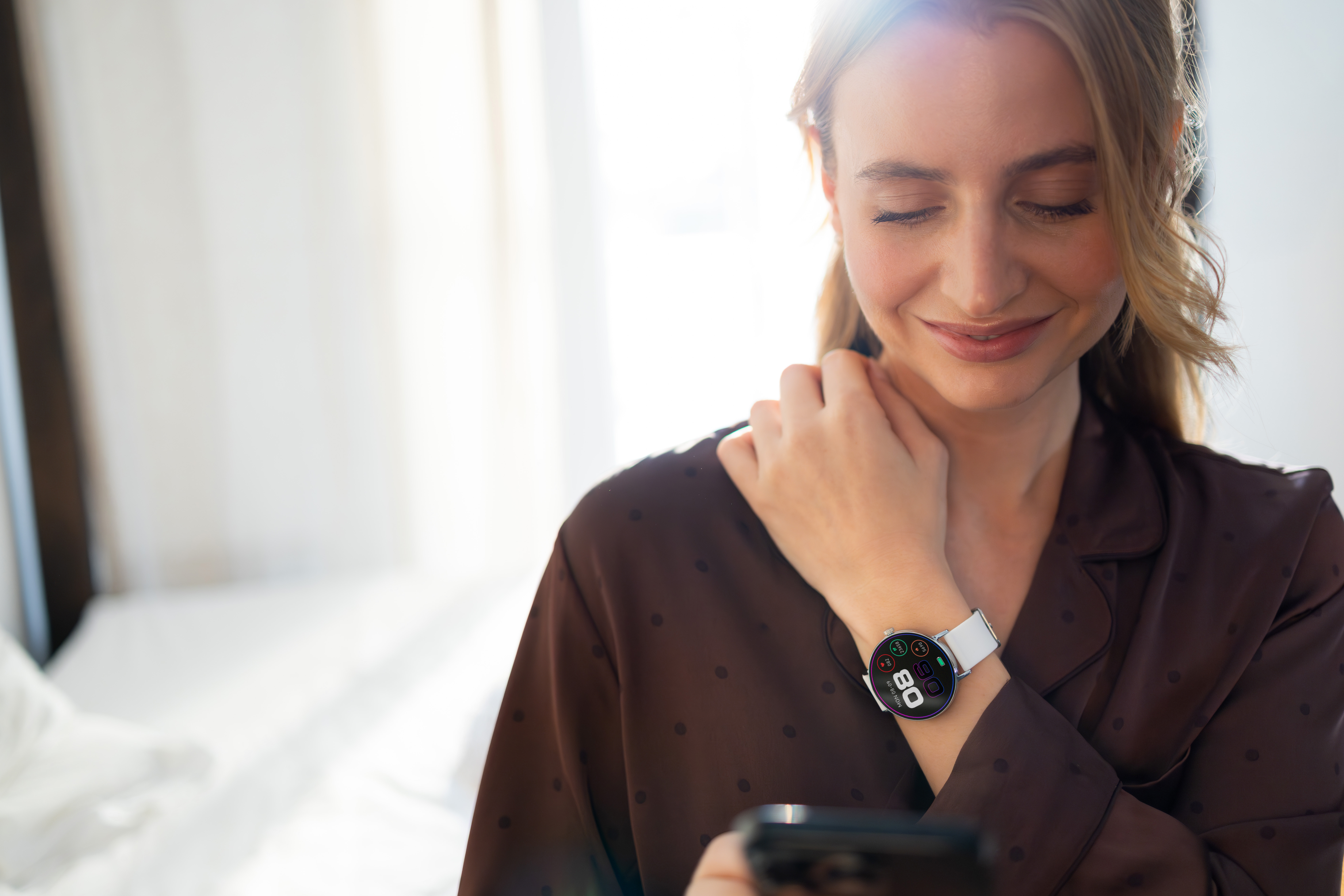 Eine Frau mit geschlossenen Augen trägt eine braune Nachtwäsche und eine Smartwatch.