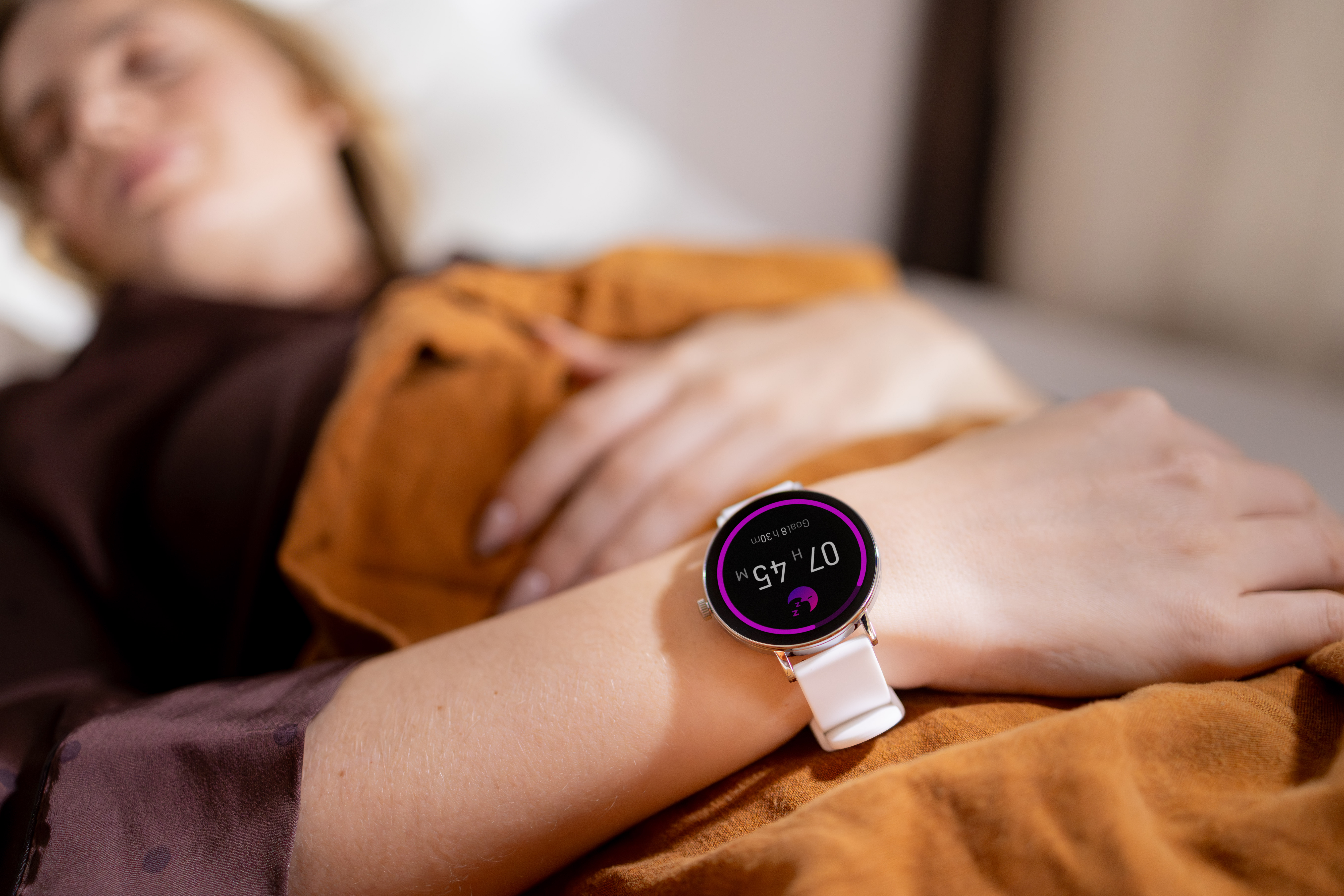 Eine Person mit einer weißen Smartwatch am Handgelenk, die 07h 45m anzeigt.